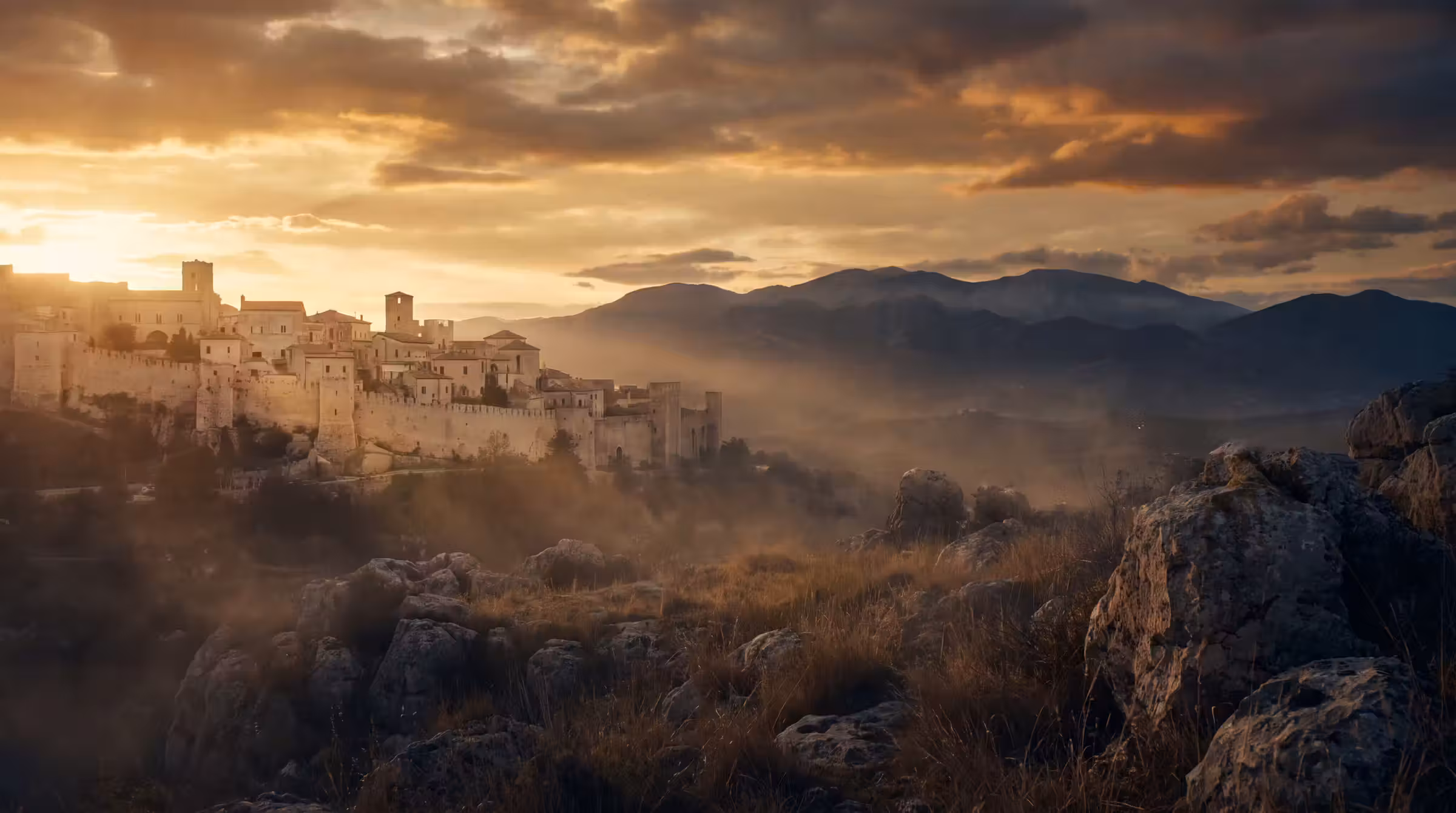 An ancient hillside city glowing under a low sun with mountains beyond
