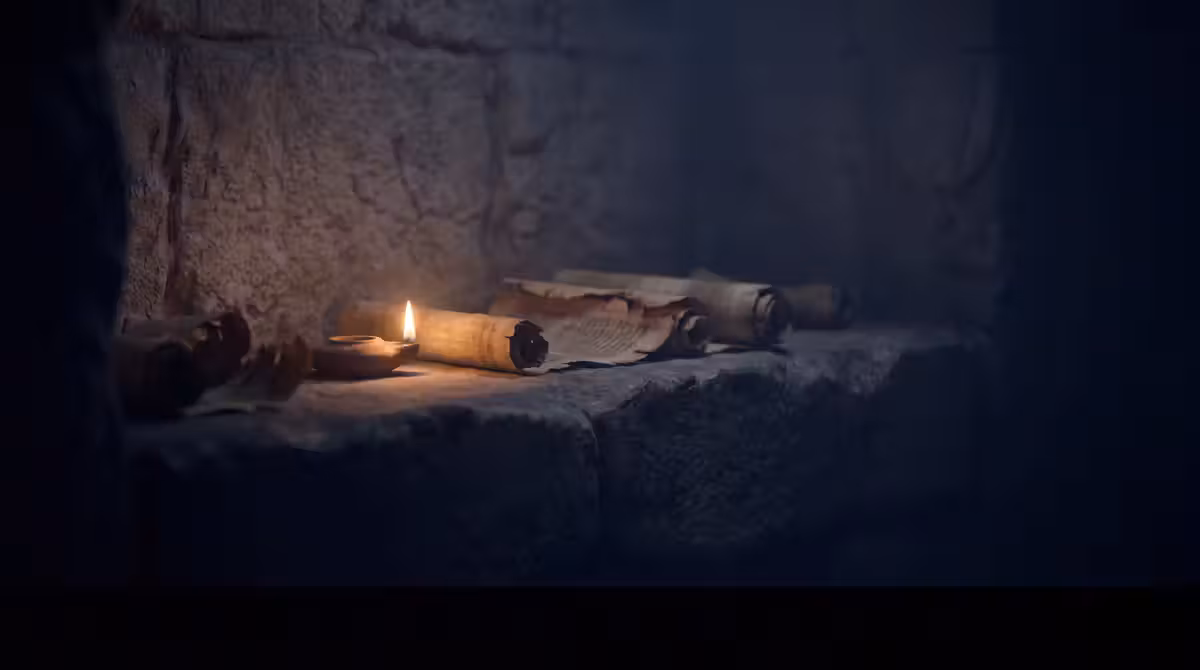 Ancient scrolls and an oil lamp beside a weathered stone wall
