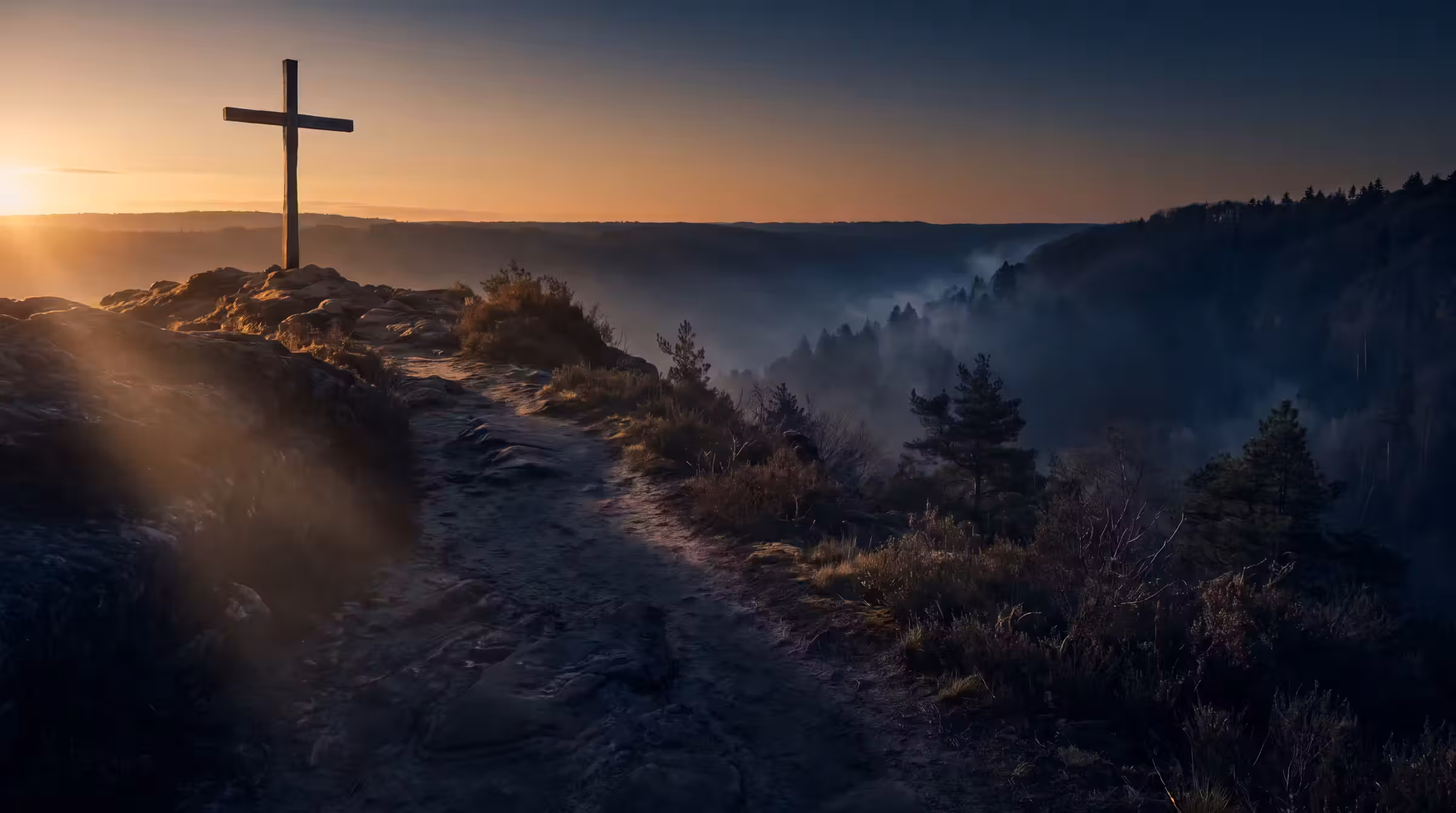 A single plain wooden cross on a ridge at dawn, above a dark mist-filled valley with one bare rock path climbing towards it
